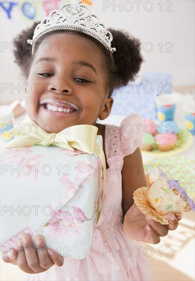 African girl eating cupcake and carrying gift