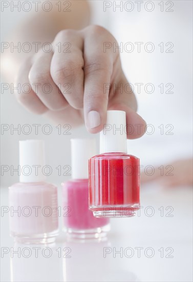 Woman choosing red fingernail polish bottle