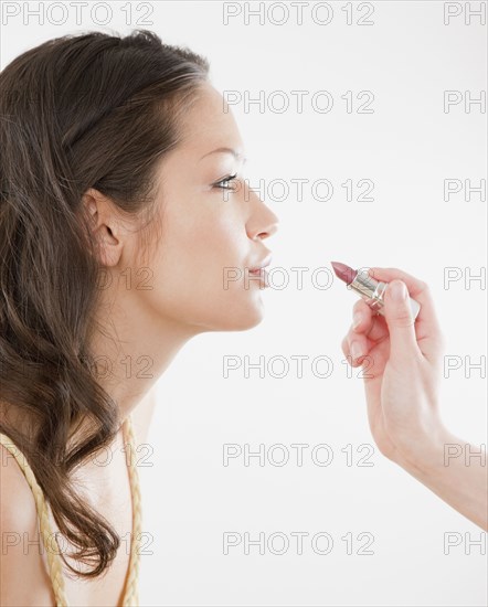 Lipstick being applied to lips of mixed race woman