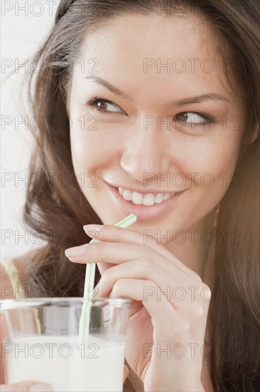 Mixed race woman drinking milk from straw