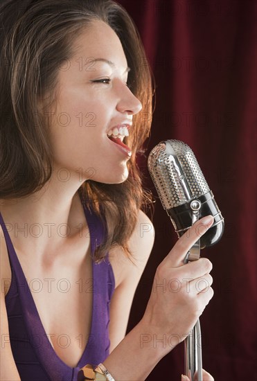 Mixed race woman singing into microphone