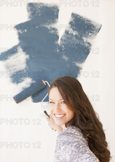 Mixed race woman painting wall