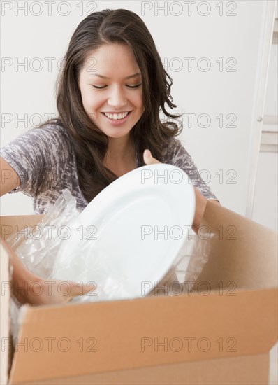 Mixed race woman unpacking dishes