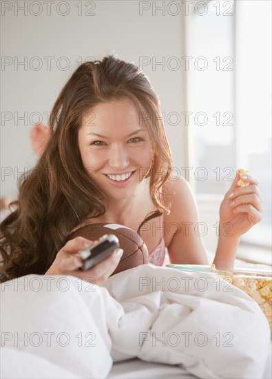 Mixed race woman watching football on television