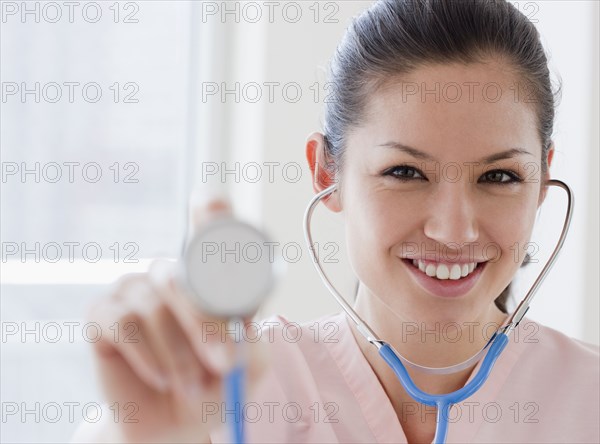 Mixed race nurse holding stethoscope