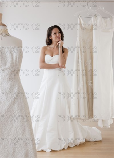 Mixed race woman trying on wedding dresses