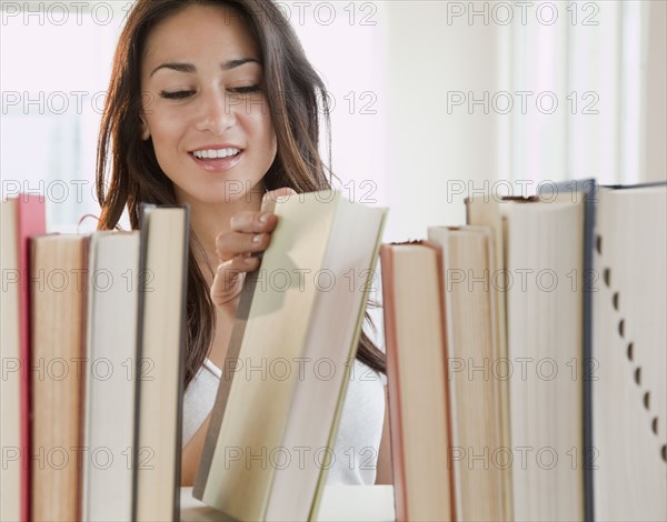 Hispanic woman removing book from shelf