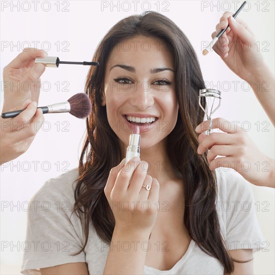 Hands applying makeup to Hispanic woman's face