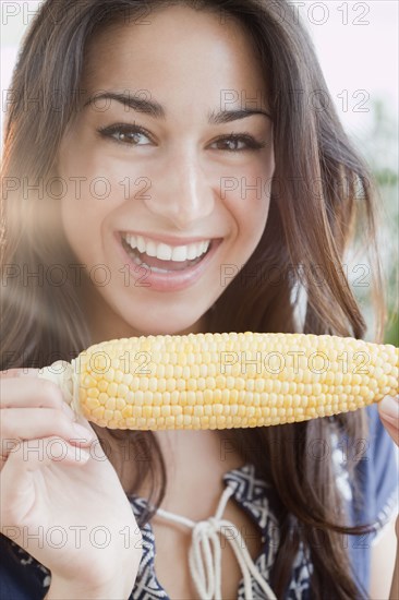 Hispanic woman eating ear of corn