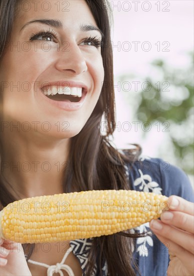 Hispanic woman eating ear of corn