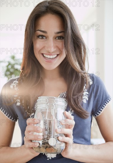 Hispanic woman holding jar of coins