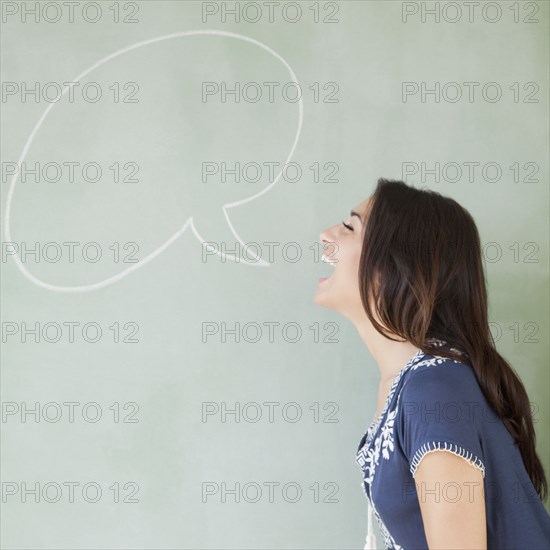 Hispanic woman with speech bubble drawn on blackboard