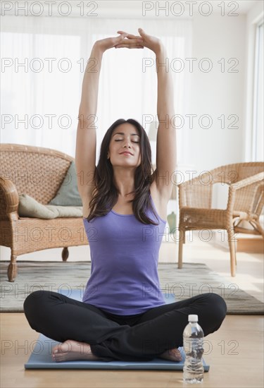 Hispanic woman doing yoga in living room
