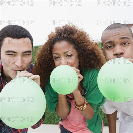 Friends blowing up green balloons