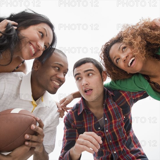 Friends holding football in huddle