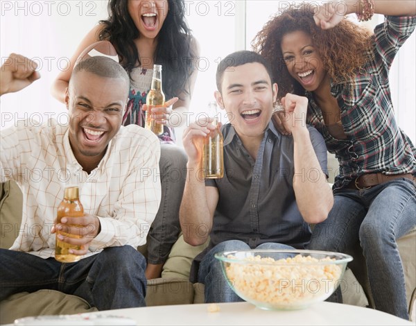 Friends drinking beer and watching football on television