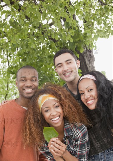 Friends holding leaf under tree