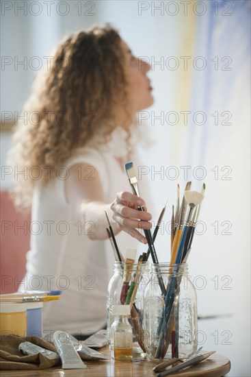 Hispanic woman reaching for paintbrush