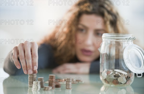 Hispanic woman counting coins from jar