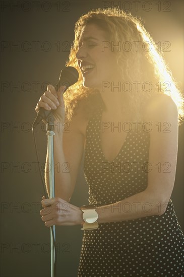 Hispanic woman singing into microphone onstage