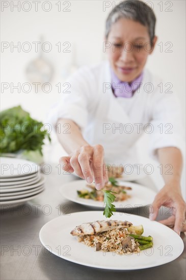 Chinese chef plating meals in professional kitchen