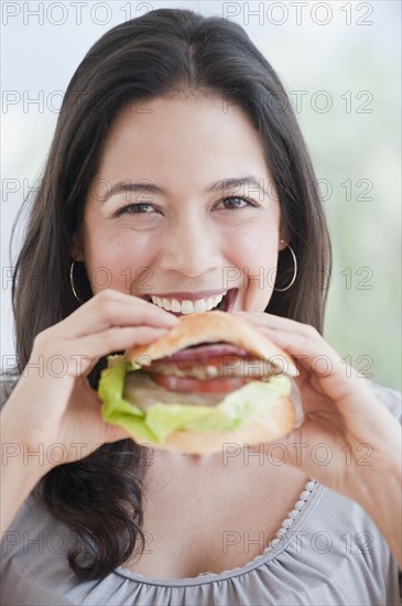 Hispanic woman eating hamburger