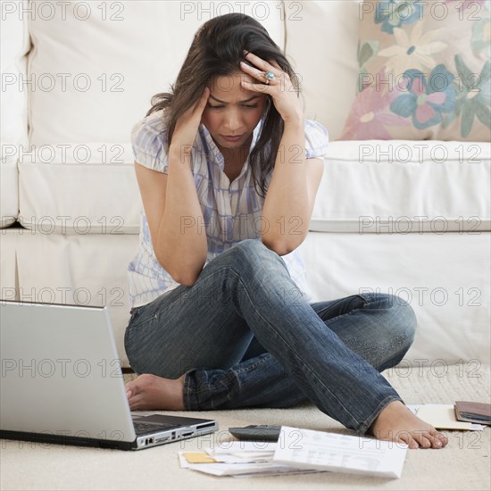 Hispanic woman looking at bills with head in hands