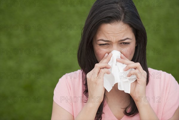 Hispanic woman blowing nose