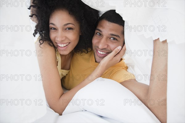 Smiling couple under bed sheet