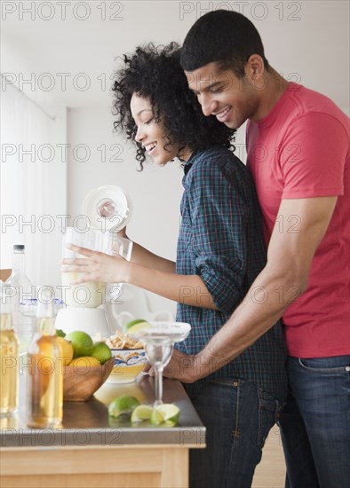 Couple mixing margaritas in kitchen