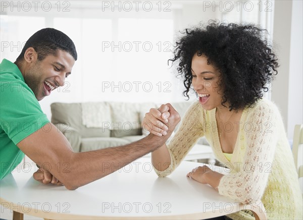 Couple arm wrestling at table