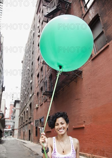 Mixed race woman holding balloon on urban street