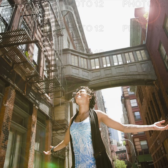 Mixed race woman with arms outstretched on urban street