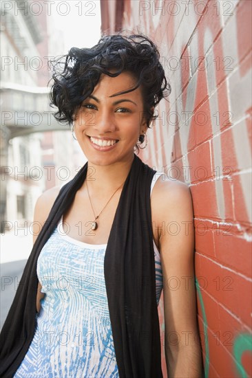 Mixed race woman leaning on urban wall