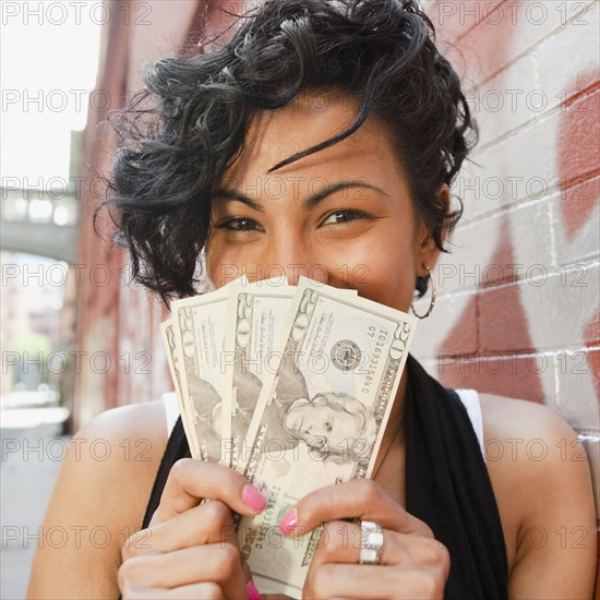 Mixed race woman holding twenty dollar bills