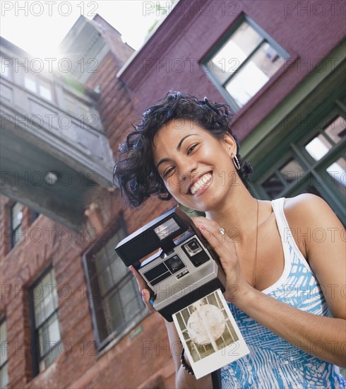 Mixed race woman holding instant camera
