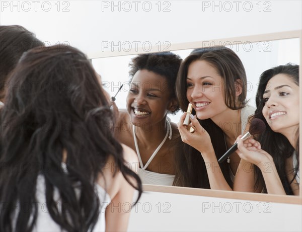 Friends applying makeup in mirror