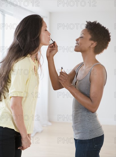 Woman putting lip gloss on friend