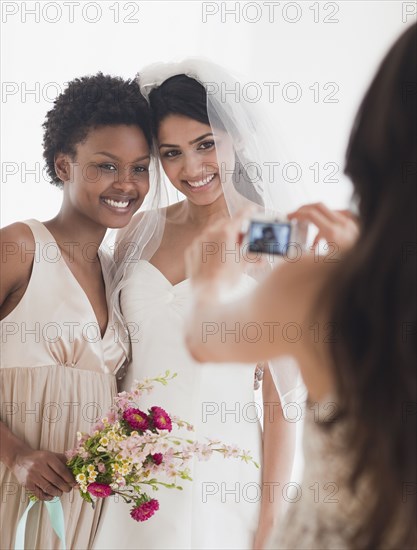 Woman taking picture of bride and bridesmaid