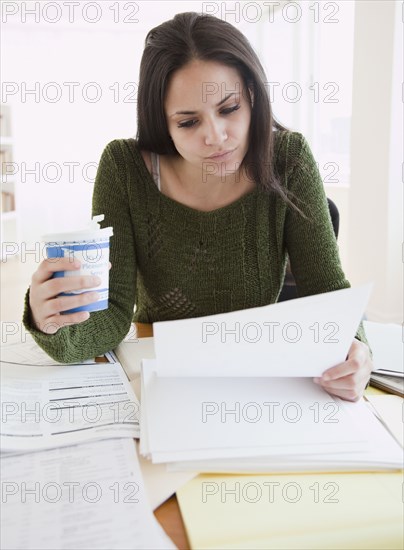 Mixed race woman working and drinking coffee