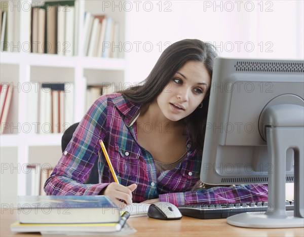 Mixed race woman doing homework at computer