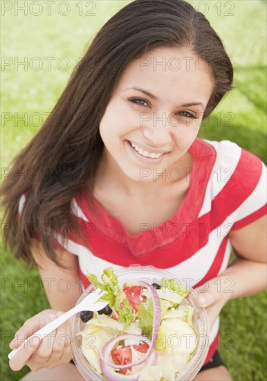 Mixed race woman eating salad