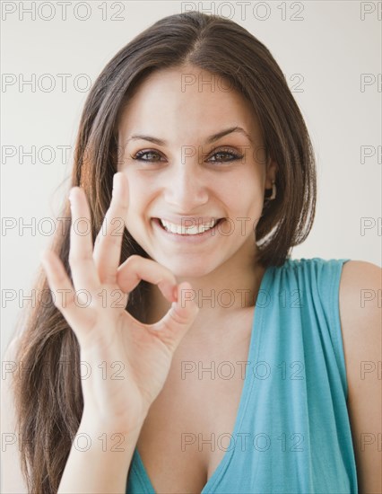 Mixed race woman making ok symbol