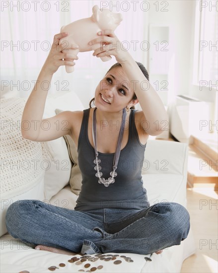 Mixed race woman emptying piggy bank