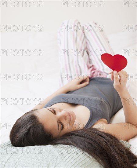 Mixed race woman holding red paper heart