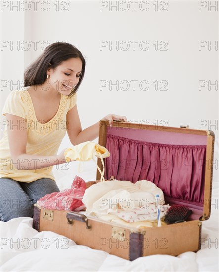 Mixed race woman packing suitcase