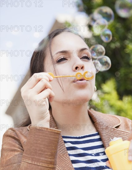 Mixed race woman blowing bubbles