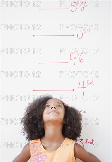 Mixed race girl standing near height chart