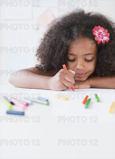 Mixed race girl drawing with crayons