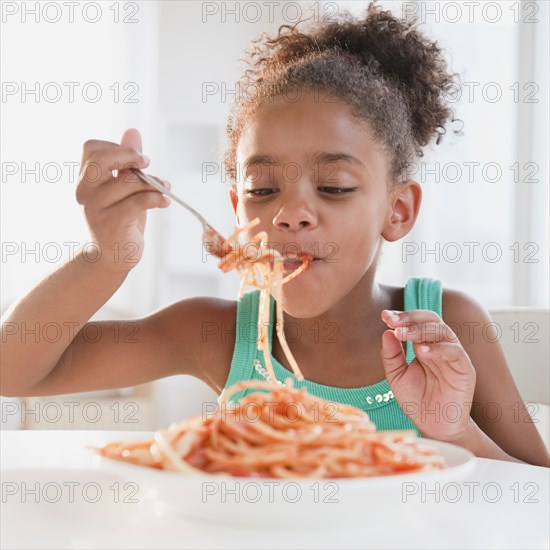 Mixed race girl eating spaghetti